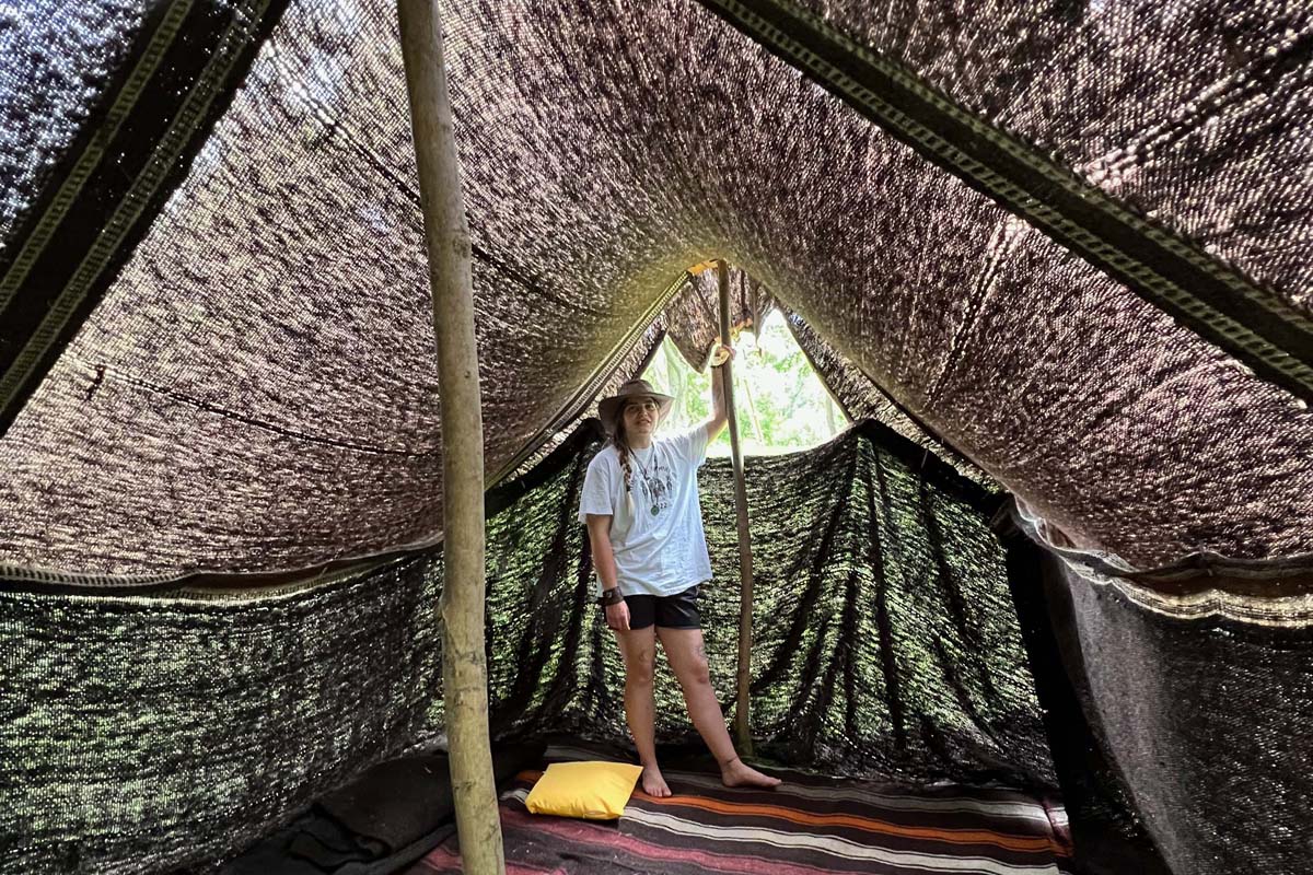 a woman standing inside a black hair tent